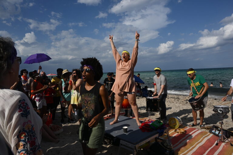 a group of people standing on top of a sandy beach