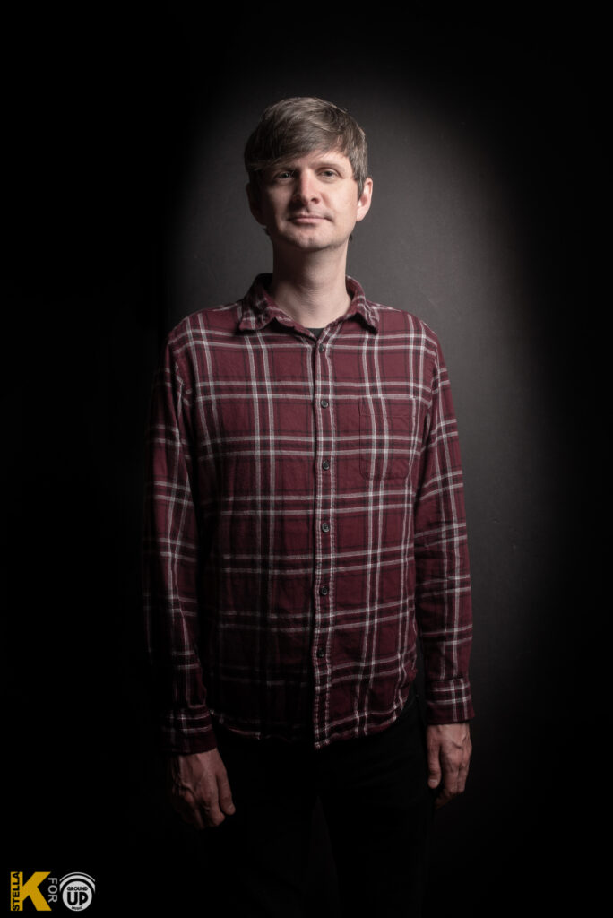 a man standing in a dark room with his hands in his pockets