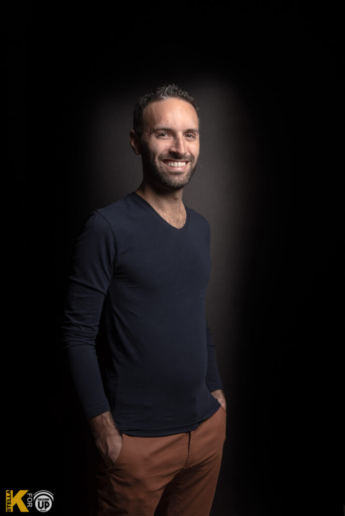 a smiling man in a black shirt and brown pants