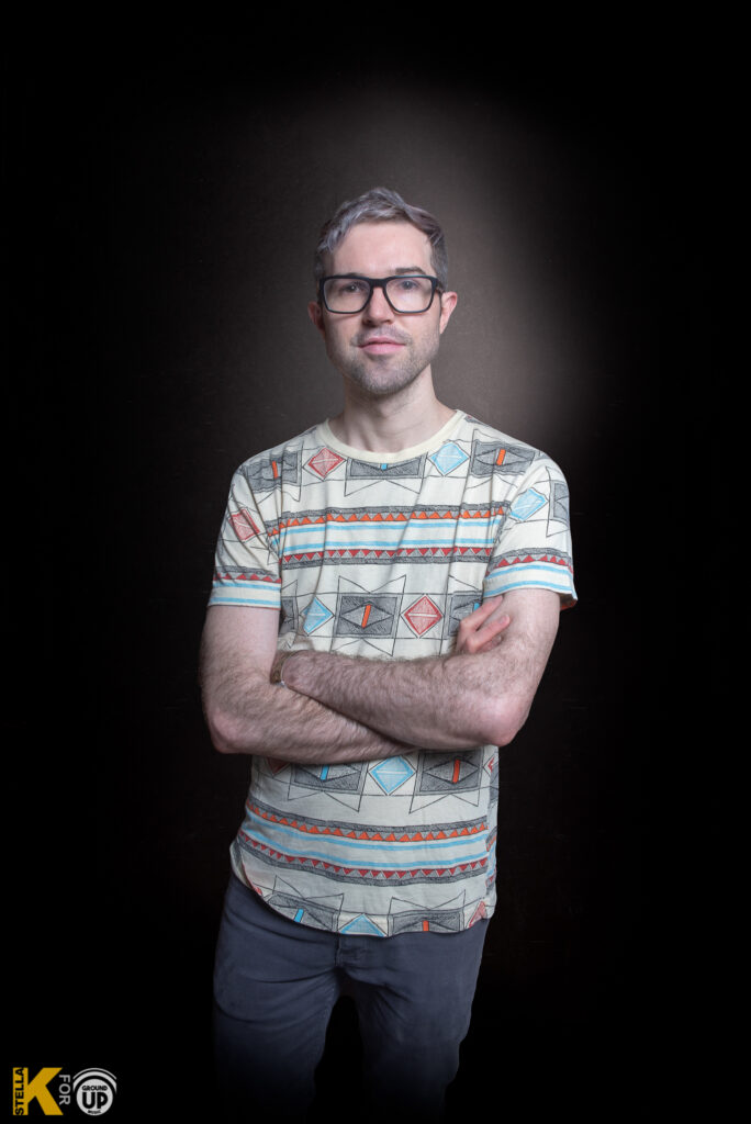 a man standing in a dark room with his hands in his pockets