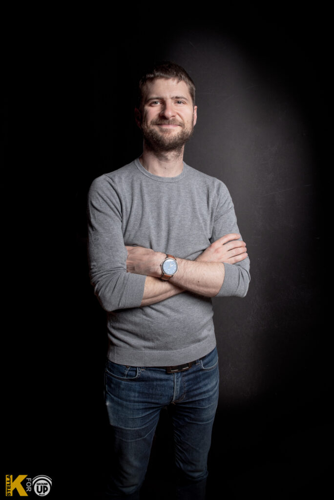 a man standing with his arms crossed in front of a black background