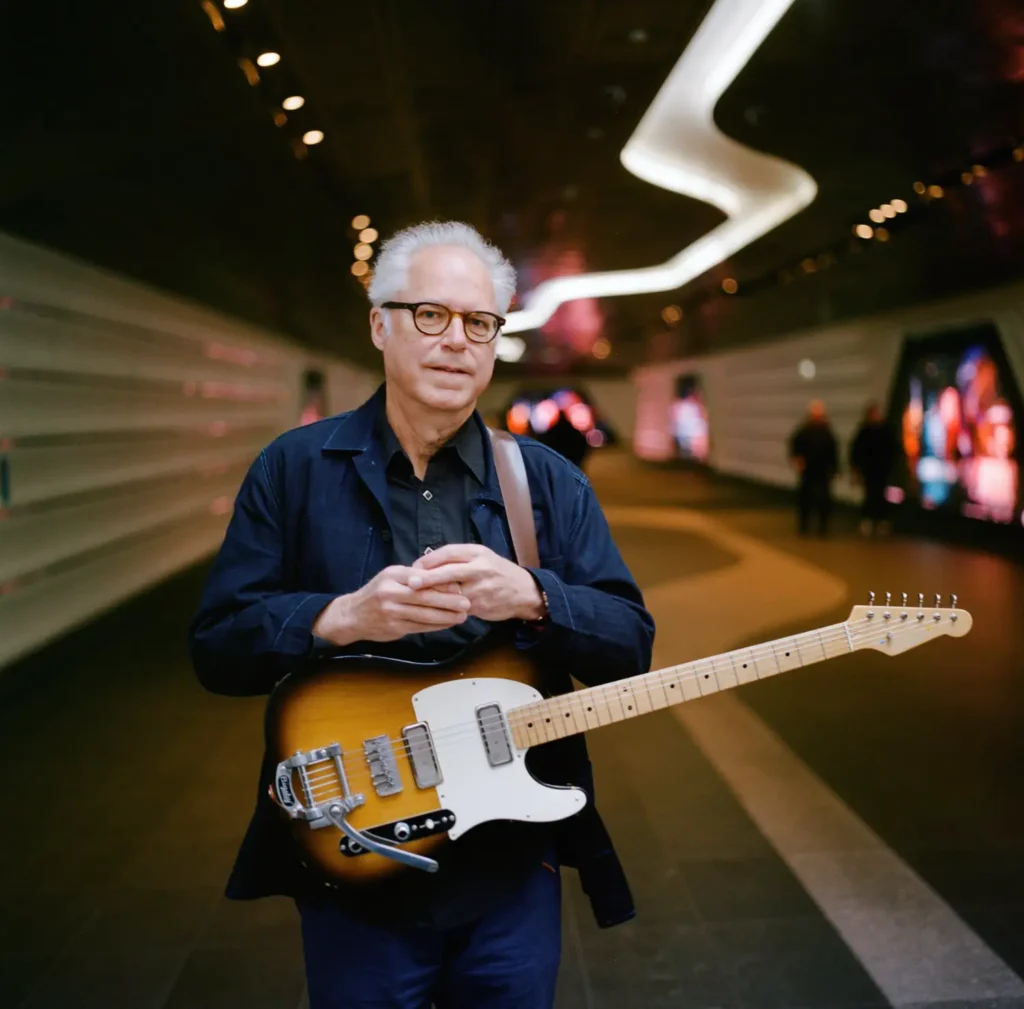 a man holding a guitar while standing in a tunnel