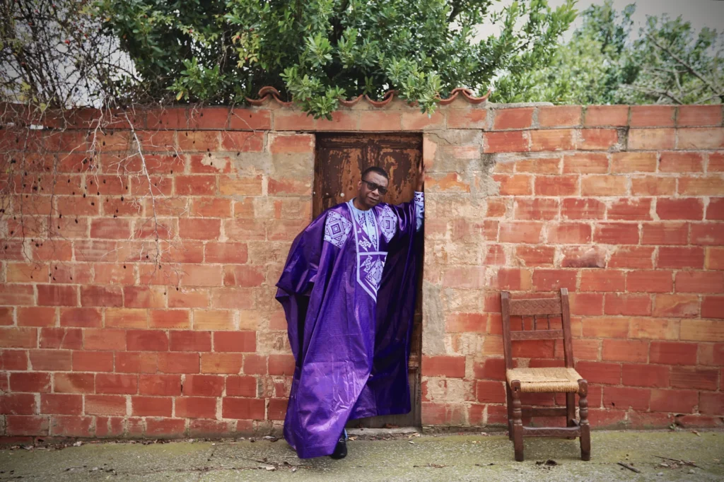 a man in a purple robe standing in front of a brick wall